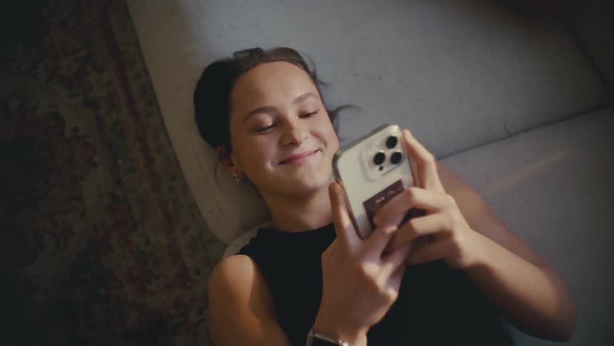 A woman is laughing while using her cell phone