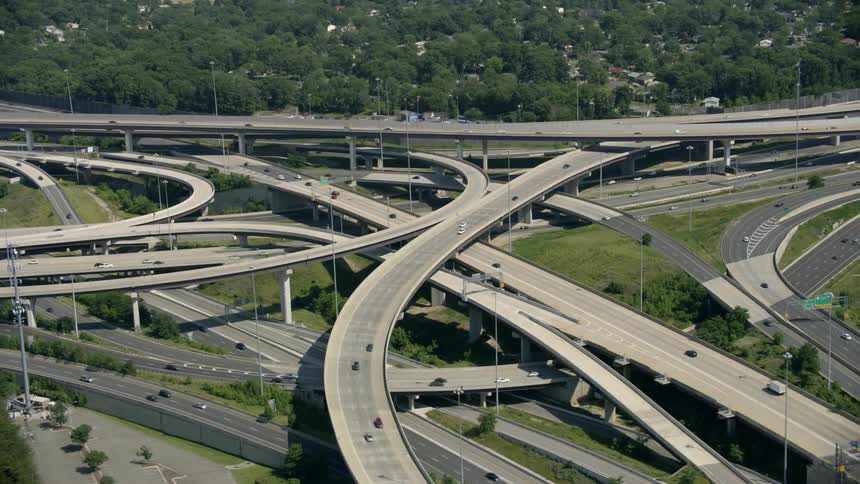 Traffic winds through a complex freeway interchange during the day