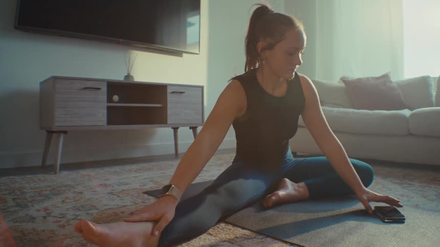 A woman is stretching on the yoga mat