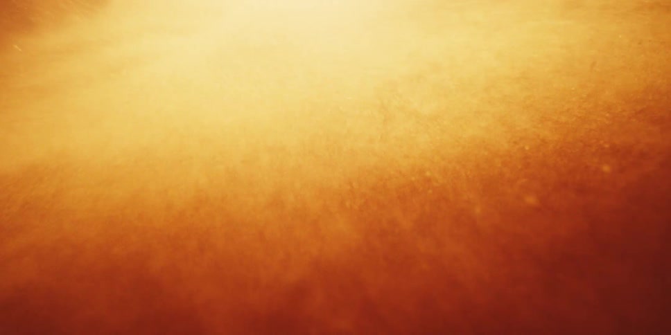 Golden particles of dust and debris smash into the lens inside an intense explosion or storm