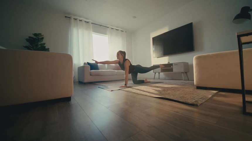 Woman stretching on a yoga mat in her living room