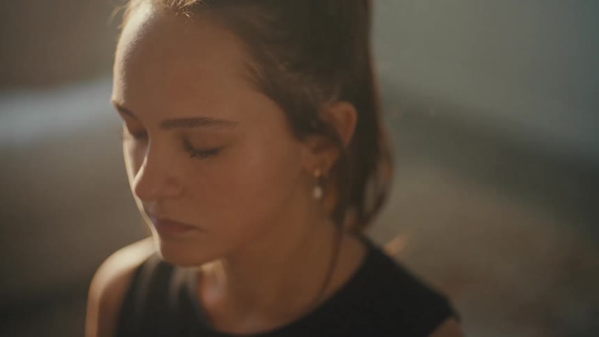A woman sits on the ground and meditates with her eyes closed