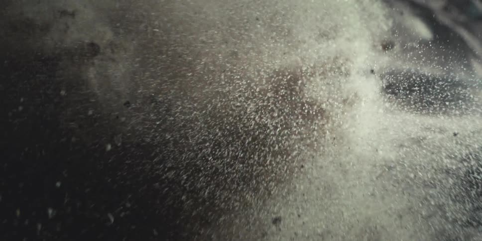 Ocean waves crash heavily due to a pouring rain storm creating clouds of mist with flying rocks
