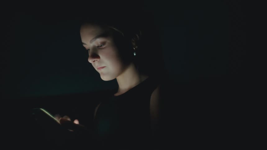 A woman is browsing the internet on her smart phone at night