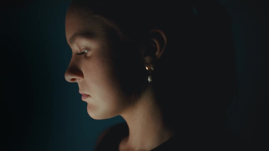 A woman has a light shining on her face in the dark