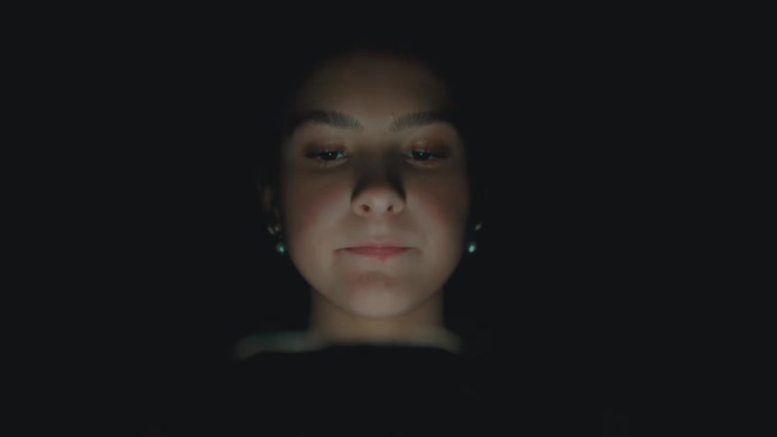 Portrait of a woman in a dark room interacting with a smartphone