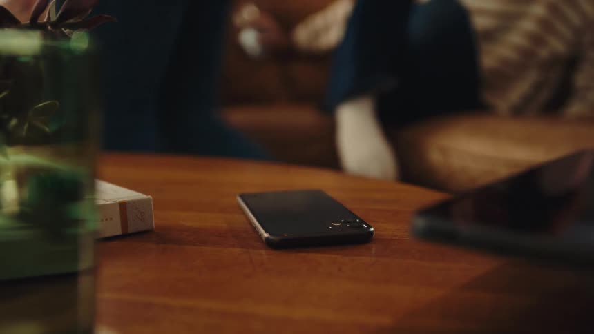 Three people drops their mobile phones on the sitting room table and walks away