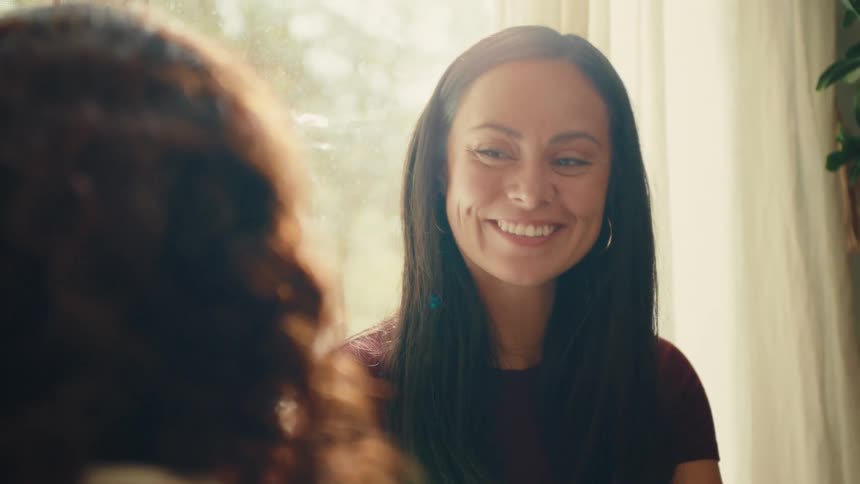 A lady smiling while having a conversation with another lady indoor during the day