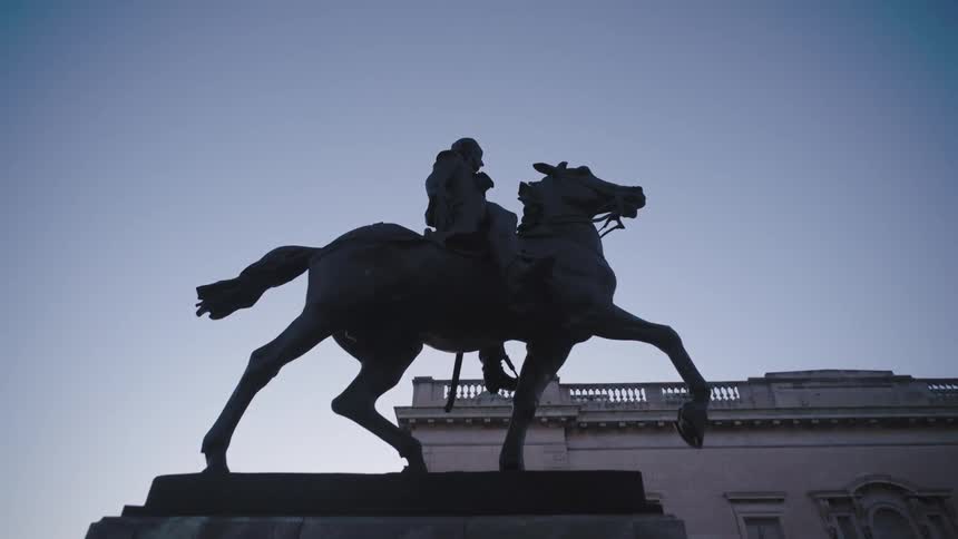 A sculpture of a monument of a man riding a horse against a blue sky