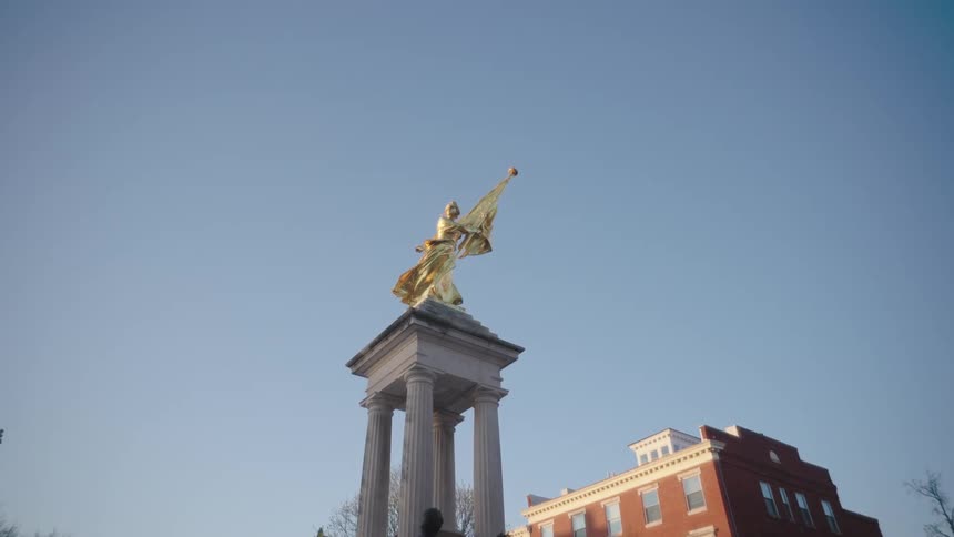A golden figure stands atop of four white pillars