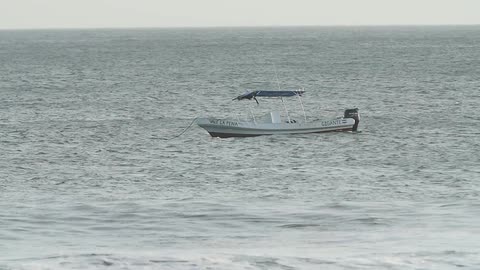 A small boat at anchor is bobbing on the tide during a windy day
