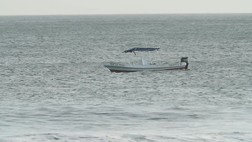 A small boat at anchor is bobbing on the tide during a windy day