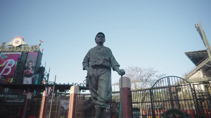A statue of a baseball player is in front of the stadium