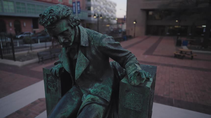 A bronze statue of a man is in front of the buildings
