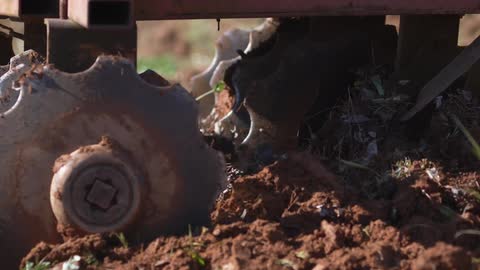 A farm vehicle is turning the dirt of a field