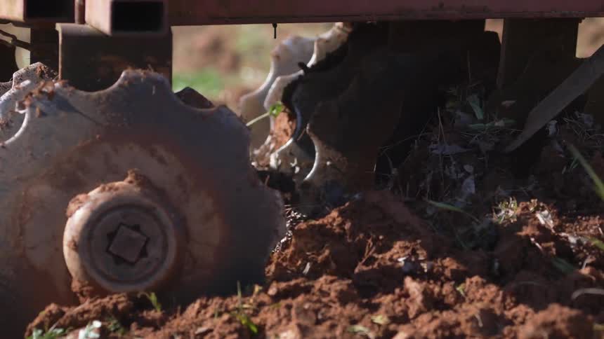 A farm vehicle is turning the dirt of a field