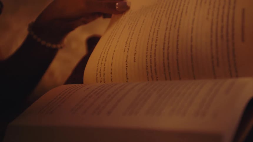 Hand of a lady opening book pages in a room