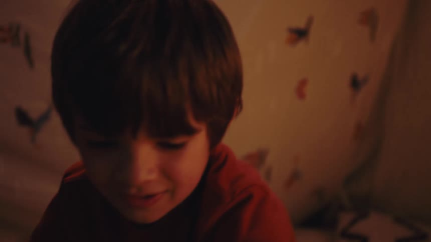A boy kneels and plays with two toys in both hands