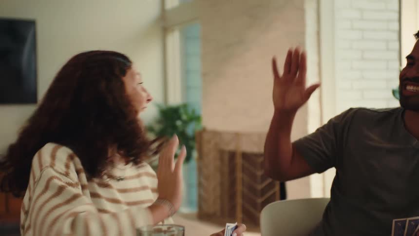 Family laughs while playing a board game at home during the daytime