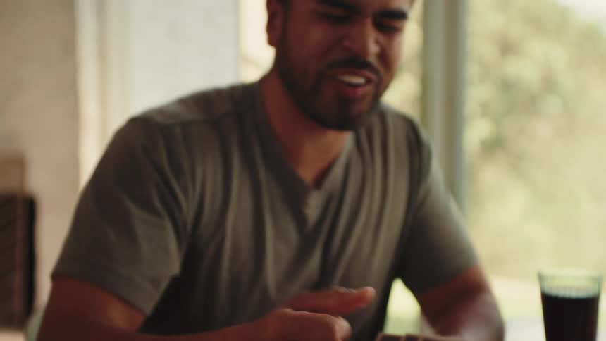 A man joyfully celebrates while playing a board game with cards and dice at a table capturing a moment of competitive fun