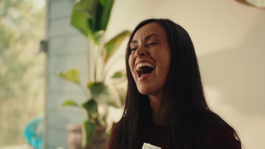 A woman holds a few playing cards in her her hand and laughs