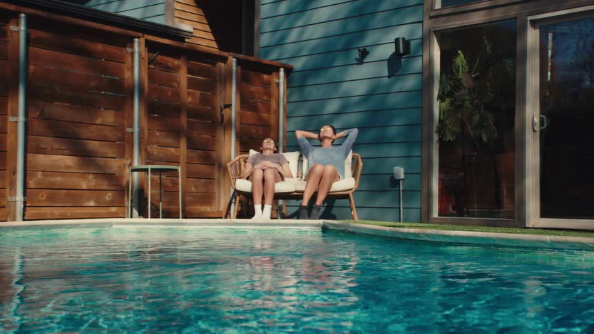 A footage of two people sitting beside a pool