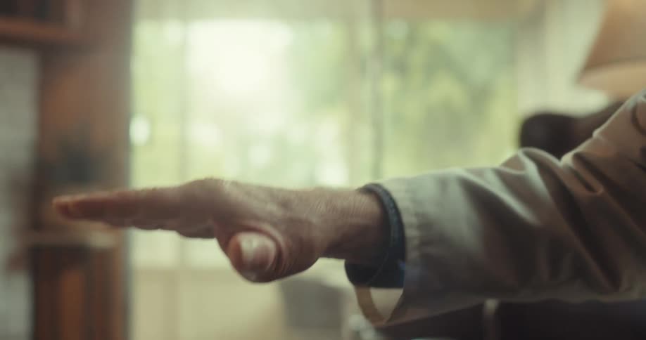 Male doctor uses his hands to demonstrate while sitting in the living room during a home healthcare visit
