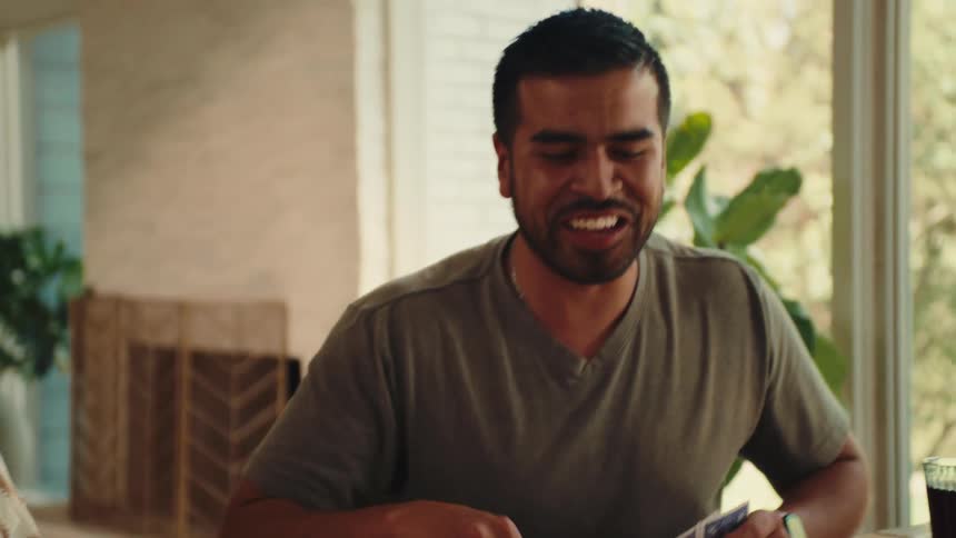 A man and a teenage girl are smiling as they sit playing a board game