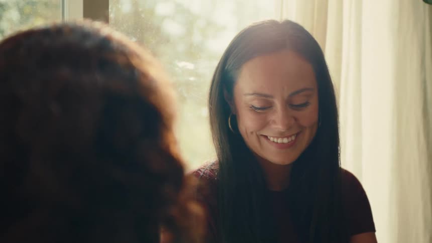 A woman smiles and laughs as she converses with another person