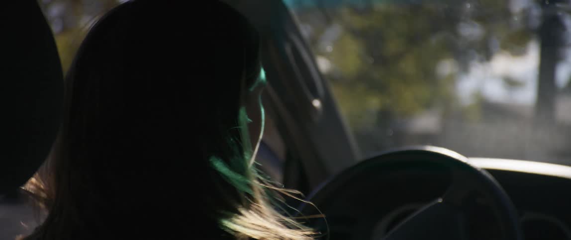 A woman looks from side to side as she steers to turn while driving
