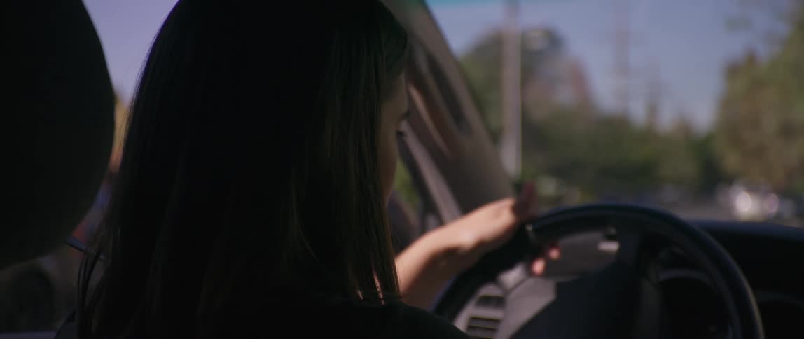 A female teenager backs a car out of driveway