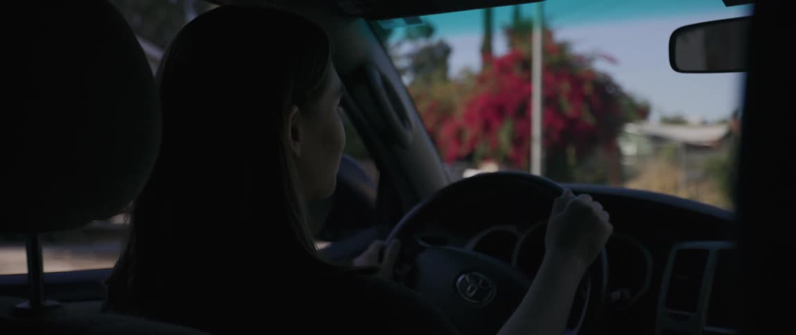 A woman turns the steering wheel as she drives