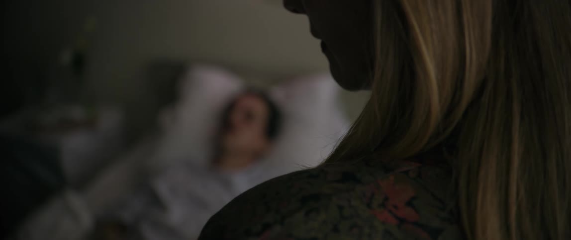 Woman in foreground watching a man lying on a hospital gurney