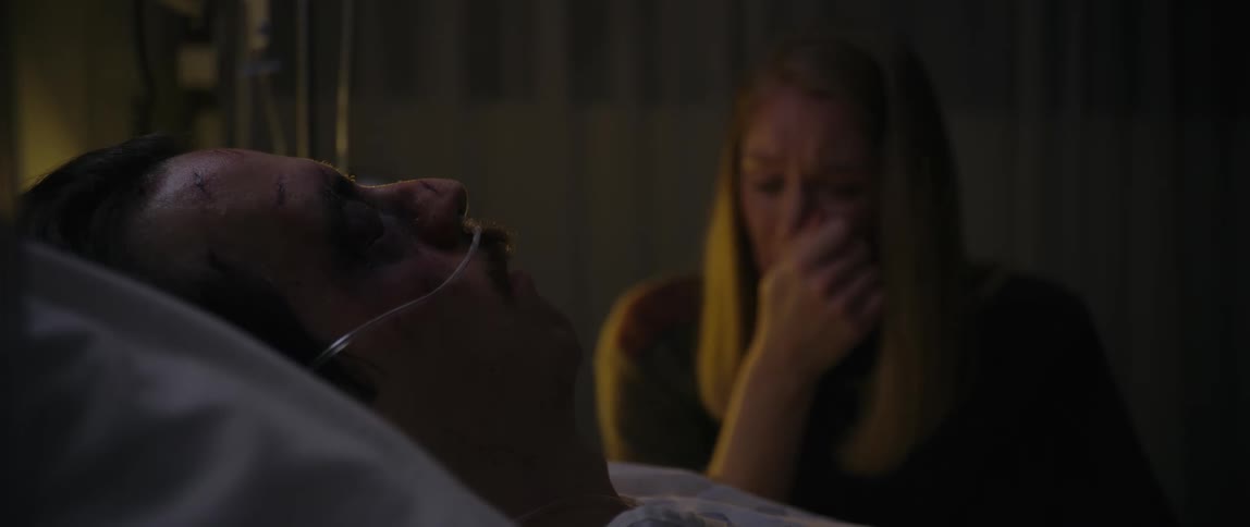 A woman is crying next to the bed of a man who is a patient