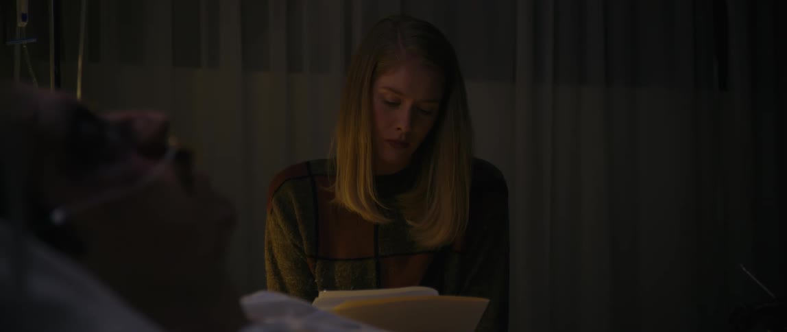 A visitor in the hospital is going over paperwork bedside
