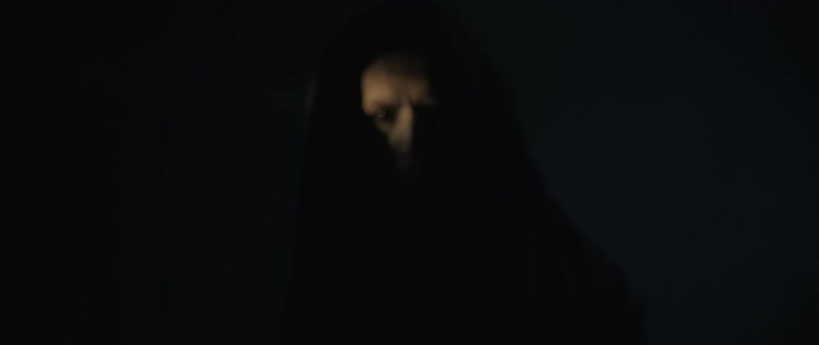 A scary man in black robes is standing in the dark
