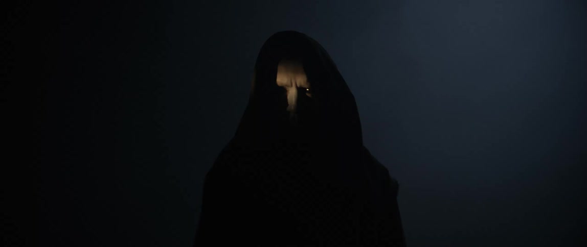 A menacing man in black robes is standing in the dark