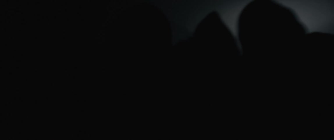 A scared man is carried away in the dark by a group of people dressed in black