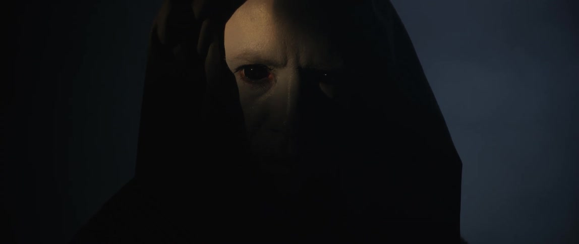 Creepy man with pure black eyes wearing a black hooded robe staring in the darkness