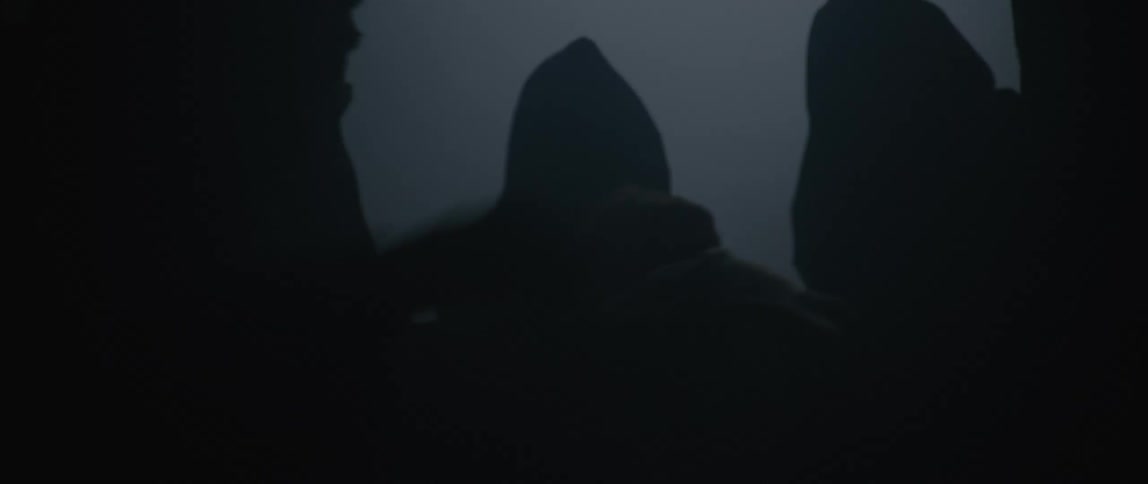 A group of people in black robes are grabbing a man as he tries to fight