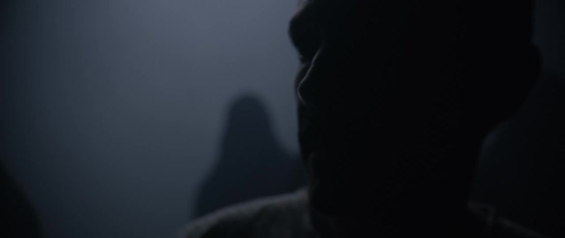 Silhouette of a man walking surrounded by hooded people