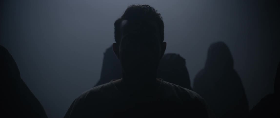 A man is being followed by people in black robes in the fog