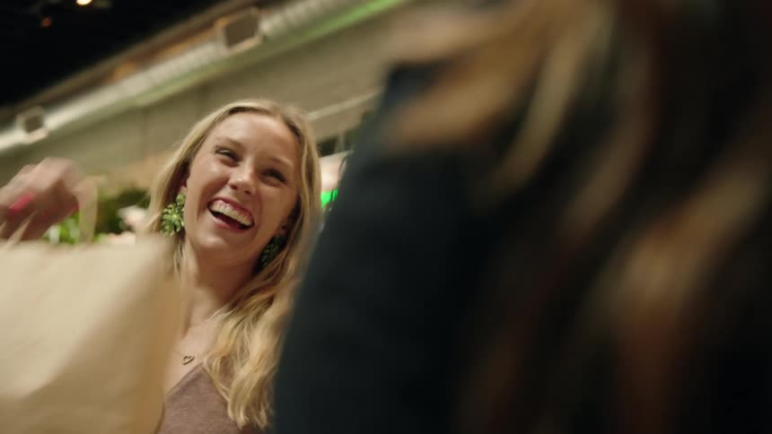 Female customer of a plant store smiles and takes her bag from the store clerk after paying