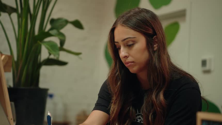 Woman writing with a pen and also typing on a laptop