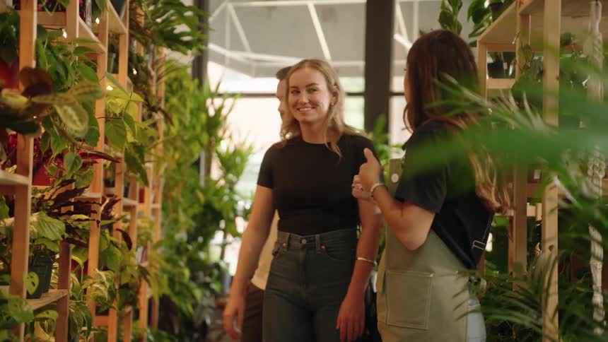 A woman shows customers plants in the store