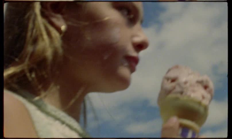 A girl licking ice cream while walking outdoor at daytime