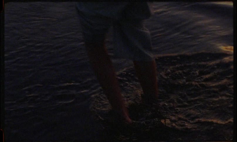 Girl walks along the shore while holding a firework