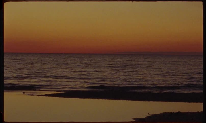 Tide gently rolling on shoreline in the afterglow of sunset