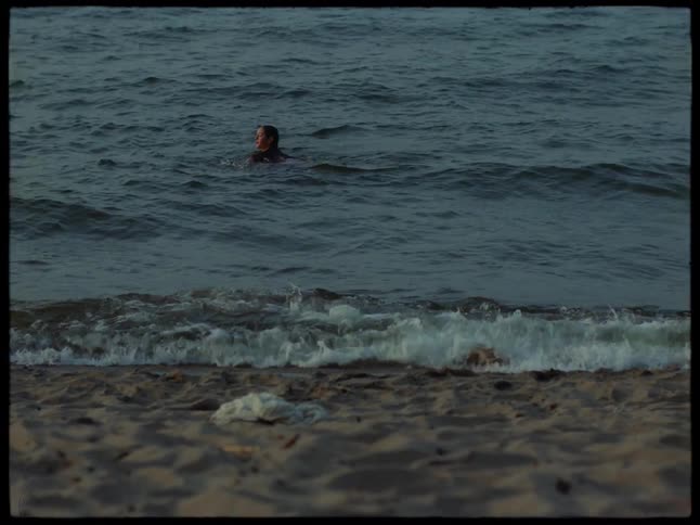 A teenage girl swims in the ocean near the beach on a summer day