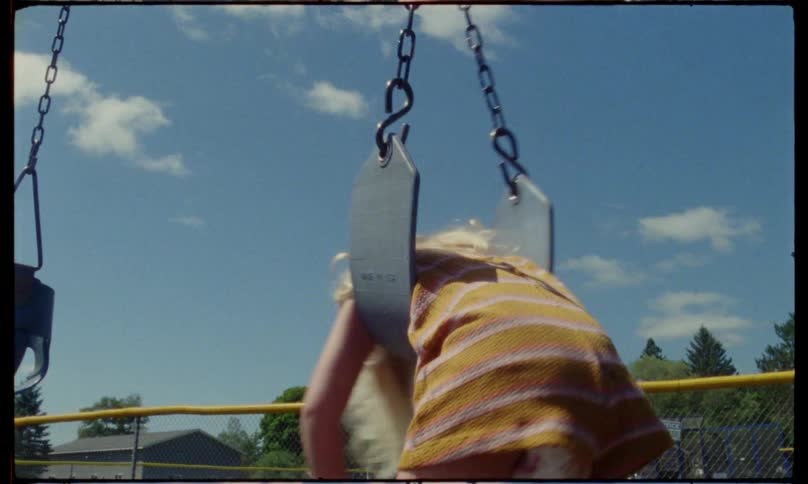 A girl is twisting on the swing in the playground